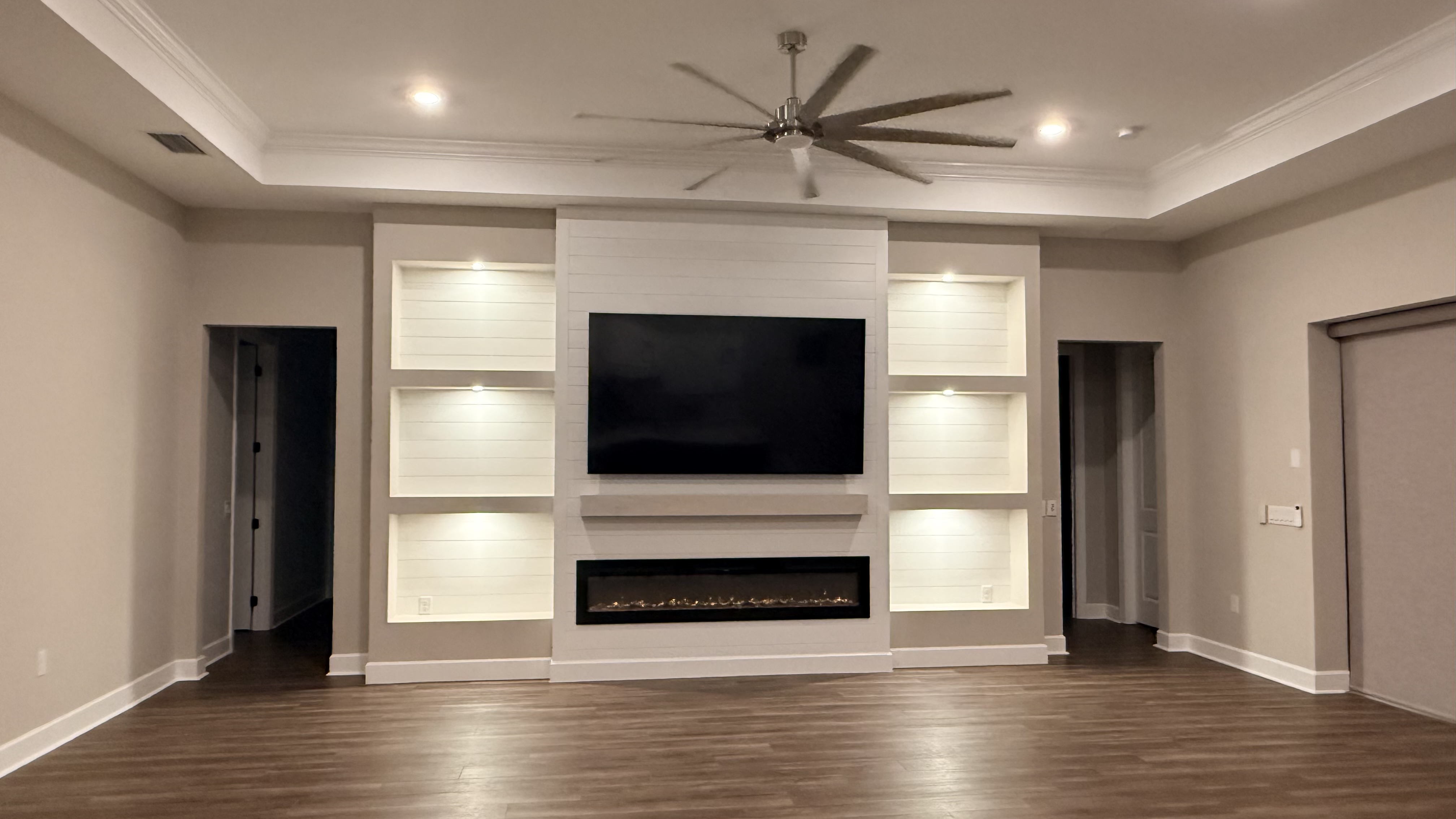 White built-in entertainment wall with floating shelves and fireplace