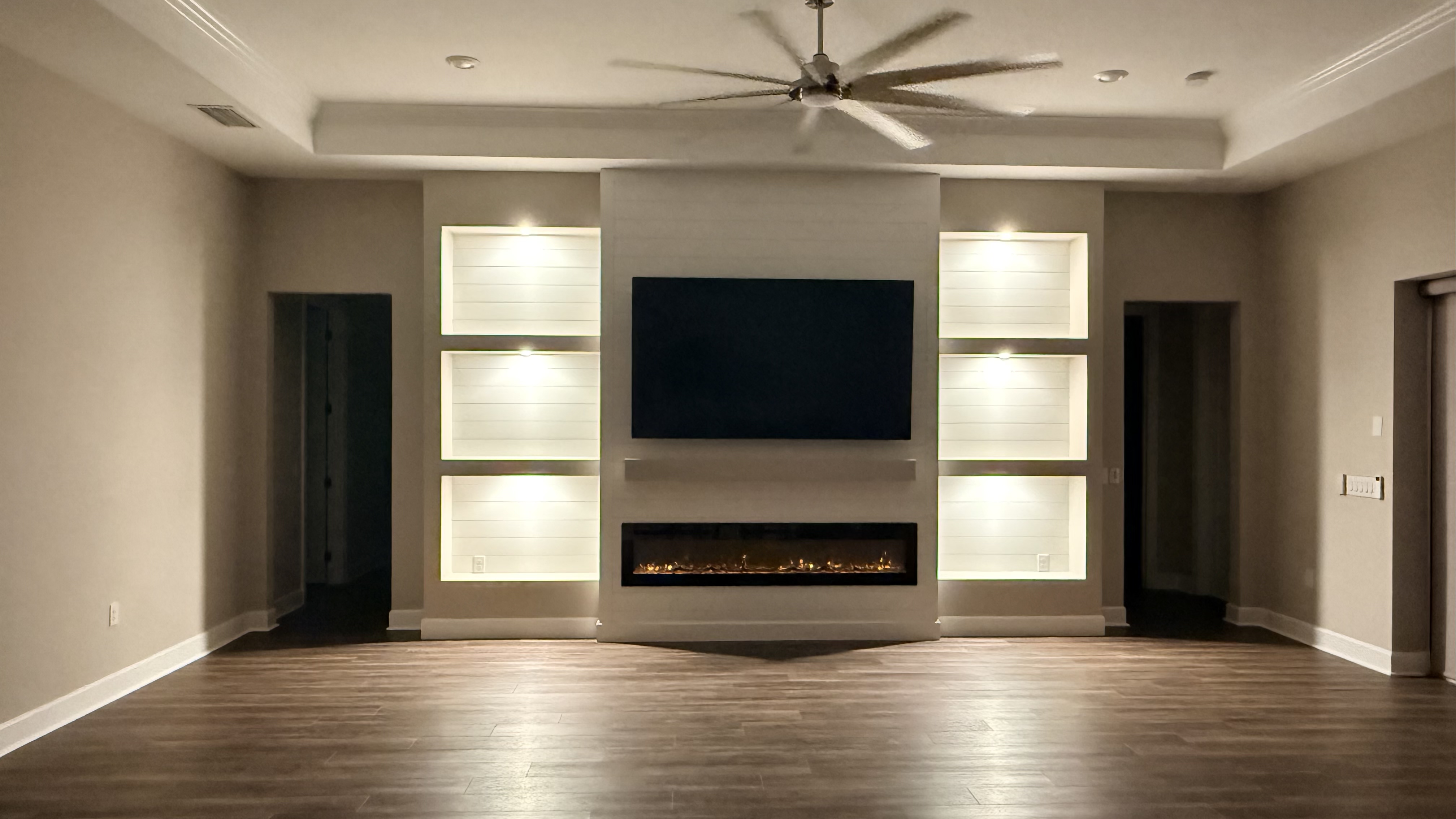 Entertainment wall with built-in cabinetry and warm lighting
