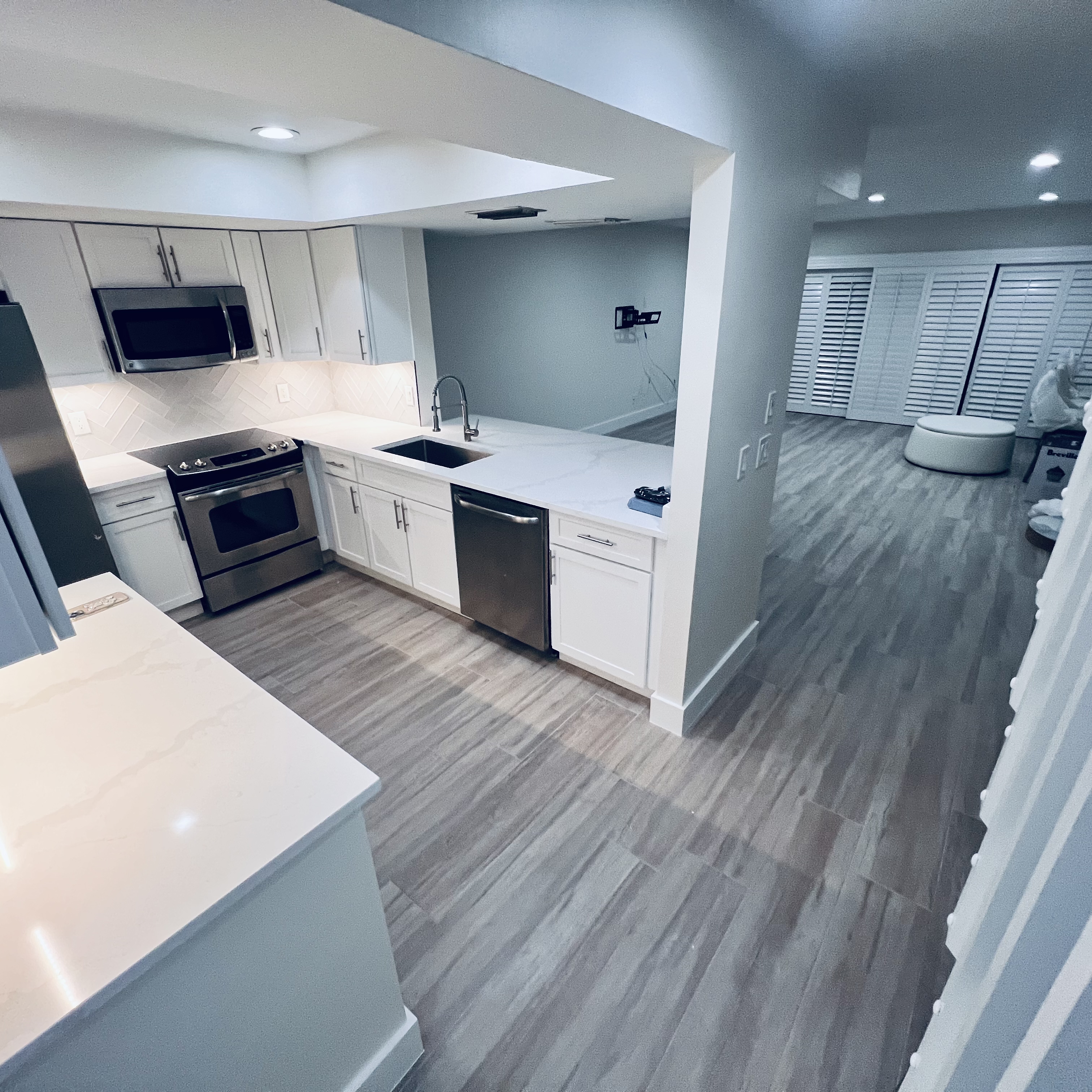 Modern kitchen renovation with white shaker cabinets, quartz countertops and herringbone backsplash